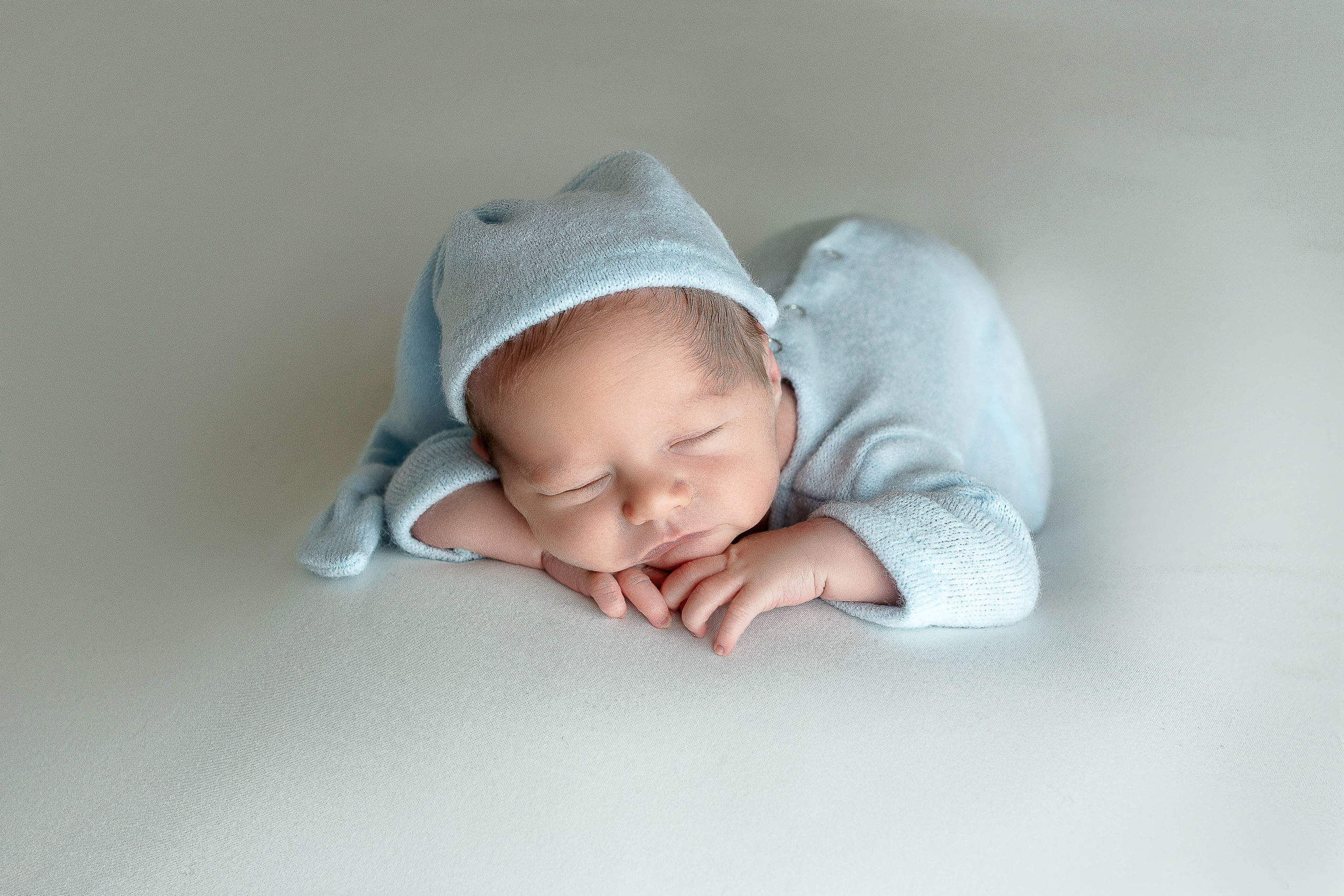 newborn baby boy laying on his belly wearing a blue outfit
