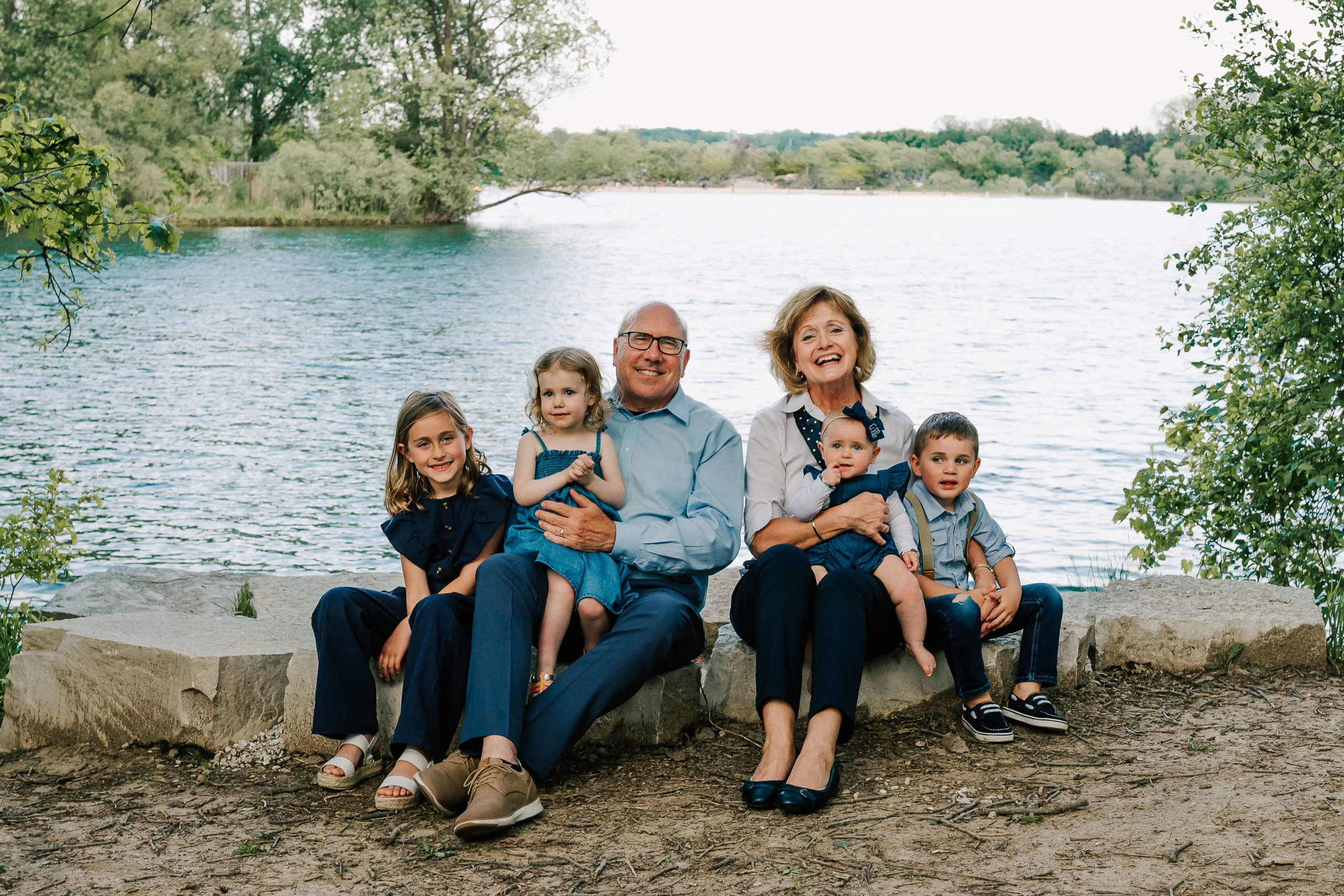 grandparents with their three grandchildren by a lake