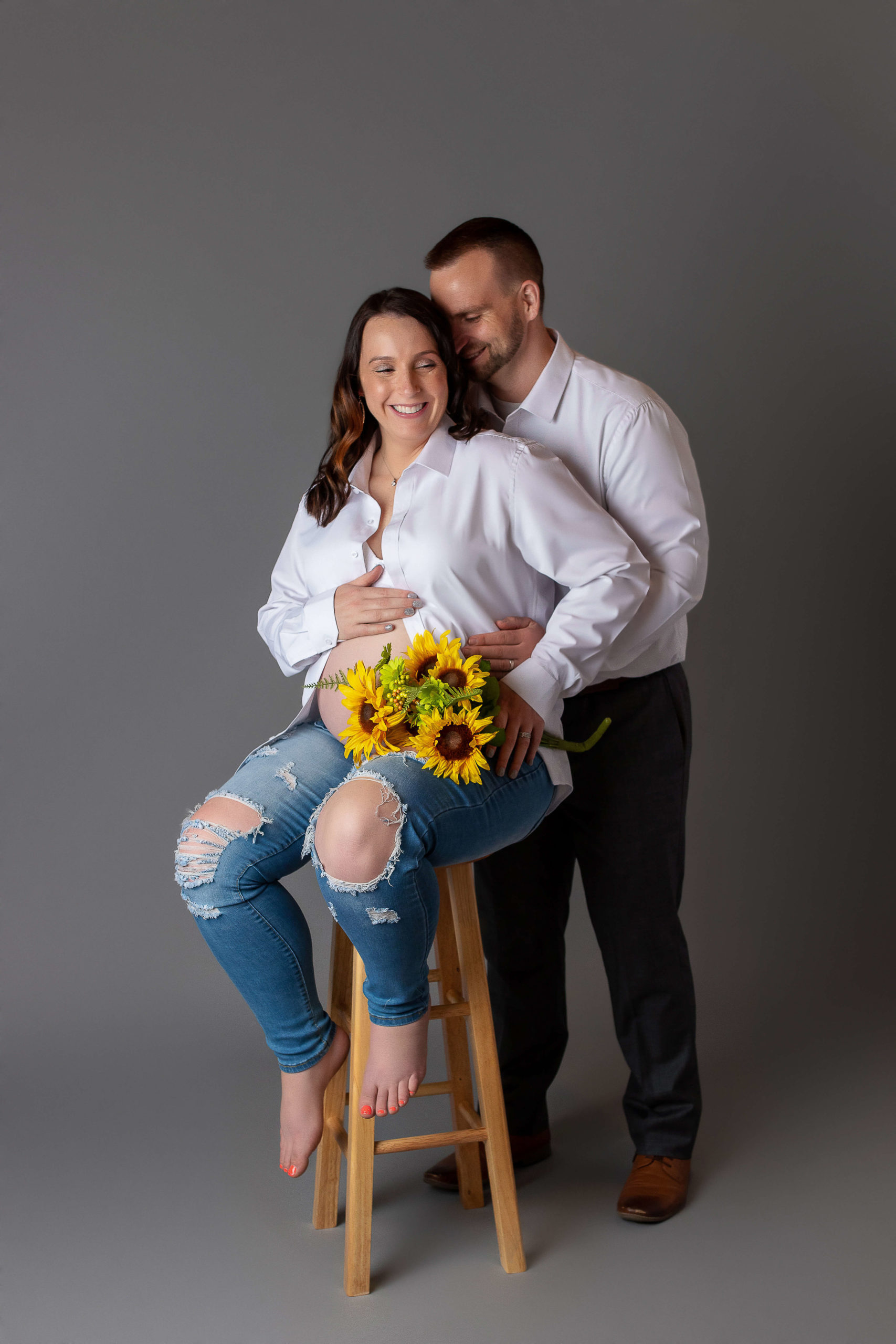 Husband embracing wife and her baby belly New Life Birth Services