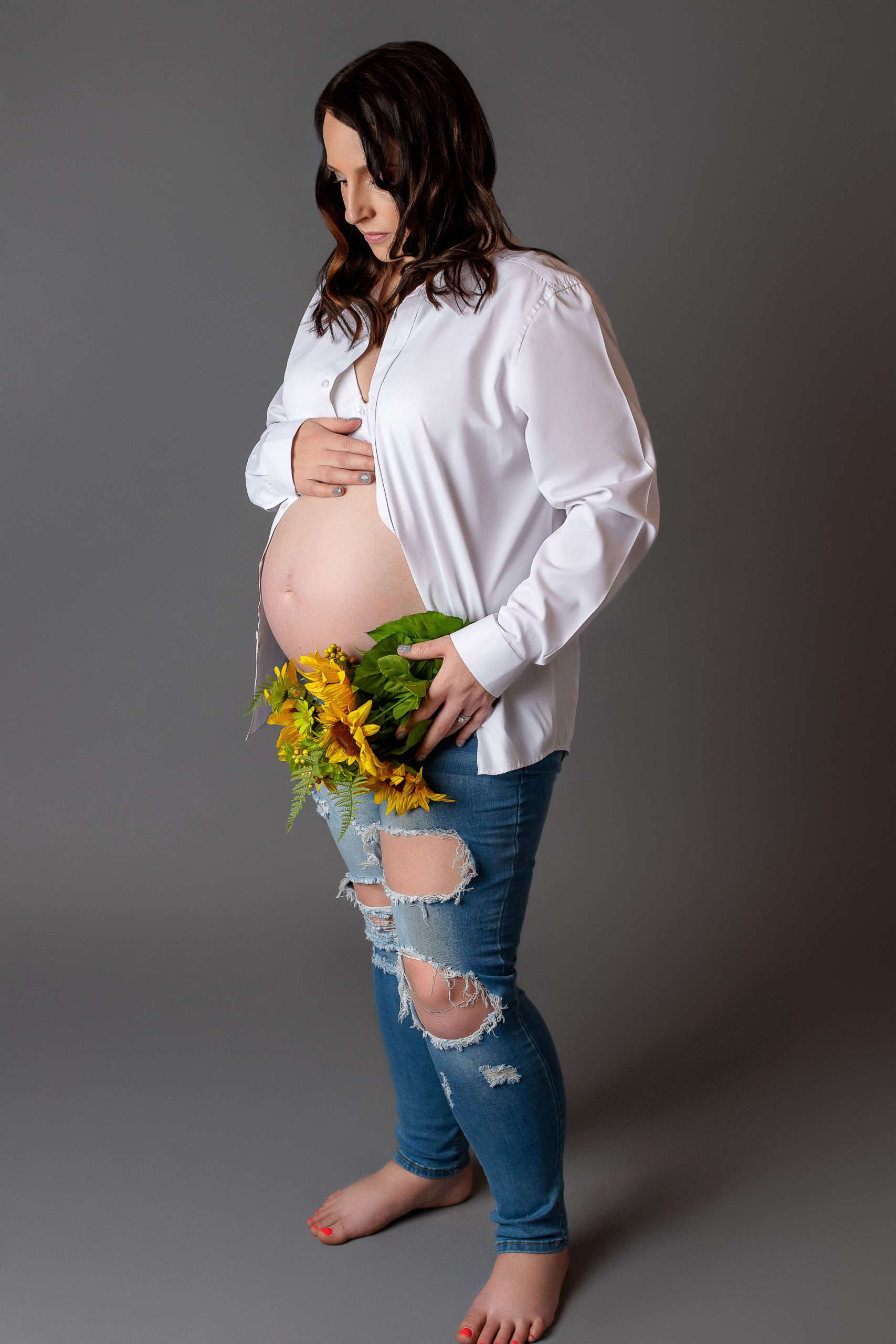 Women holding sunflowers up to her belly New Life Birth Services