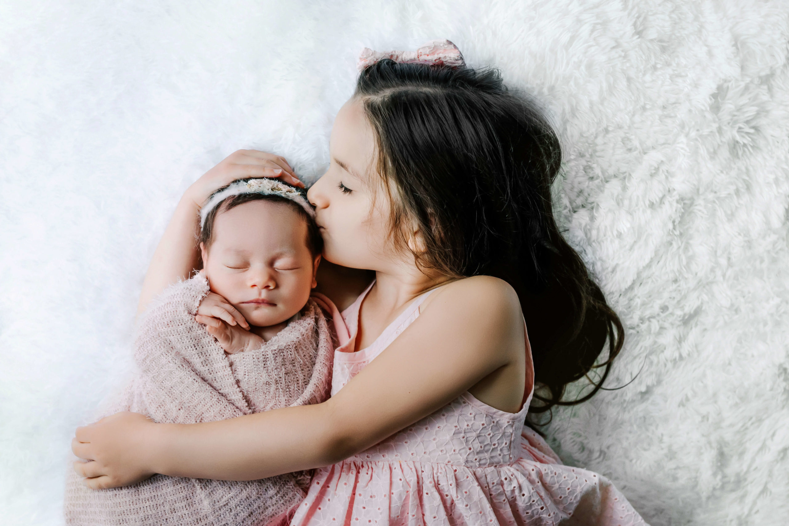 Milwaukee lifestyle newborn photographer captured an image of sisters in pink outfits