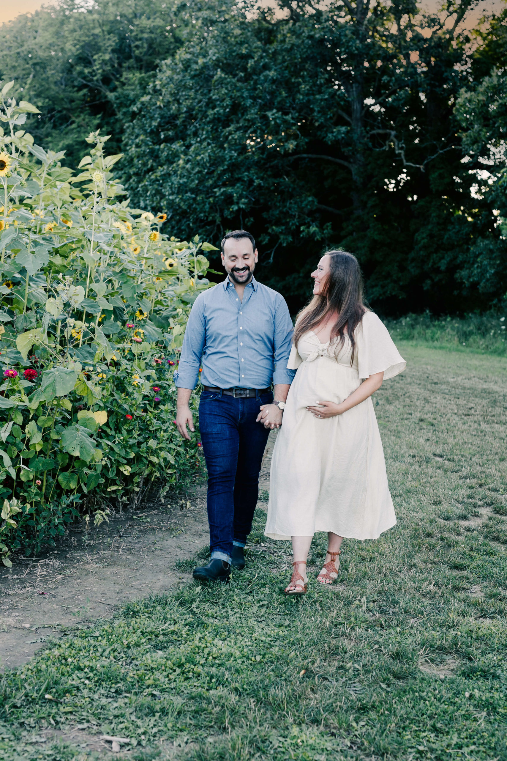 couple walking through the sunflower farm for their maternity photos