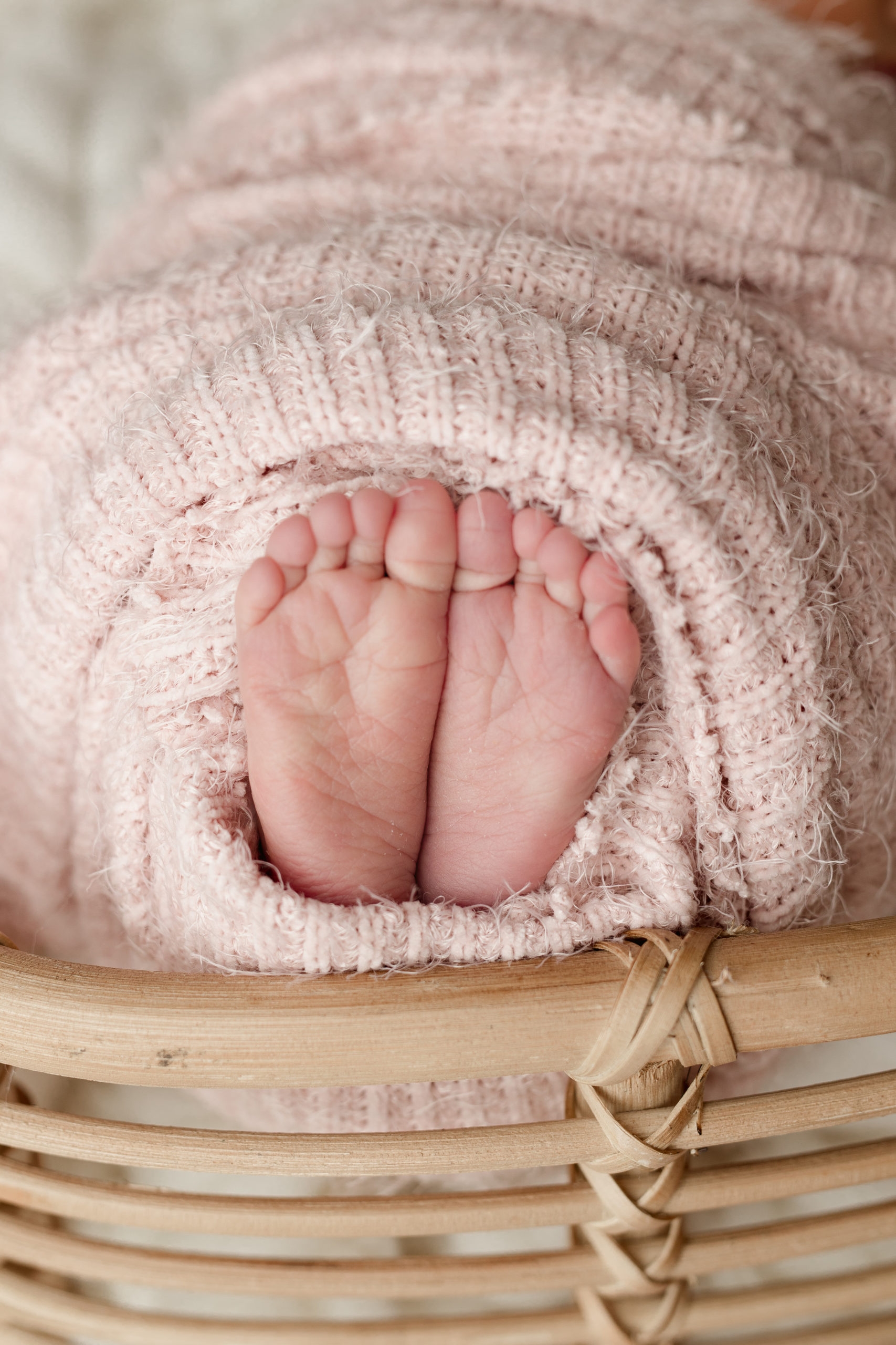 newborn baby girl feet wrapped in a light pink blanket