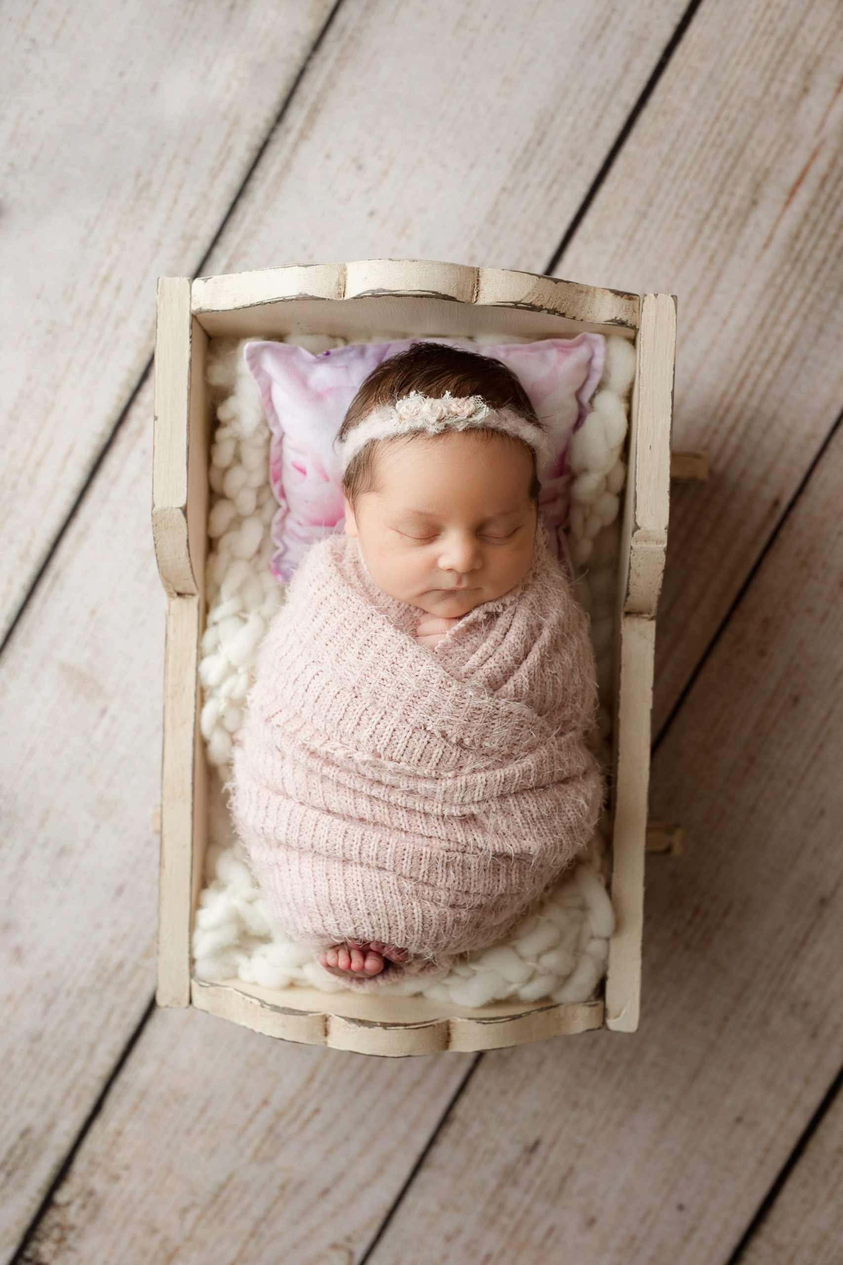 Newborn baby girl in a tan antique bassinet at a photography studio in brookfield wi