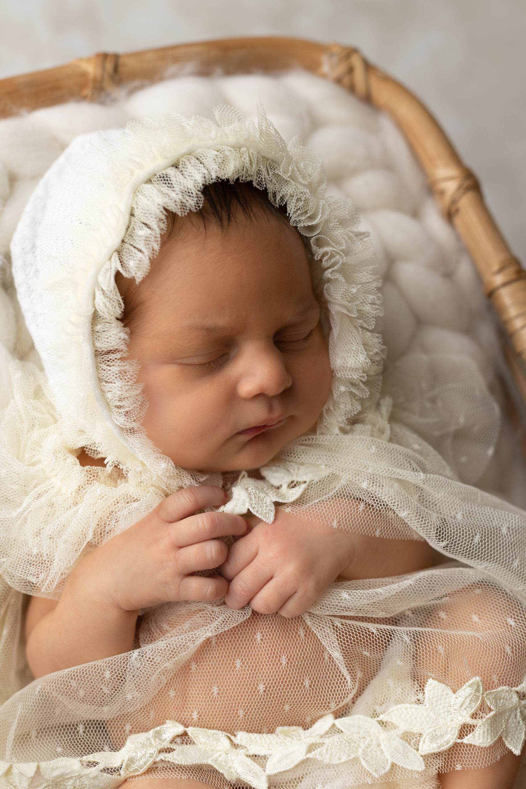 Newborn baby girl in a cream lace bonnet during a photoshoot with a Milwaukee newborn photographer