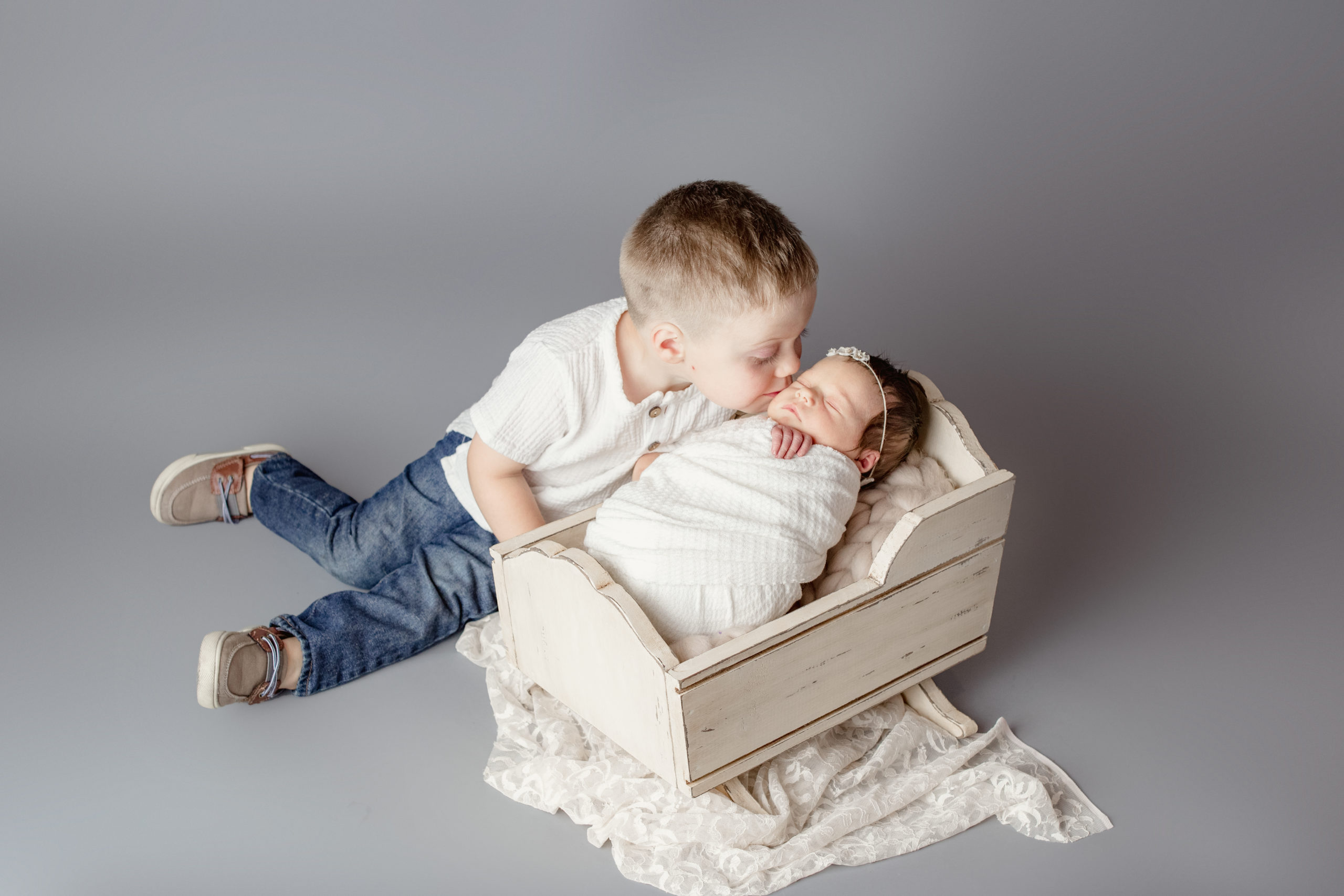 proud big brother taking a picture with his sister in a Milwaukee newborn photography studio