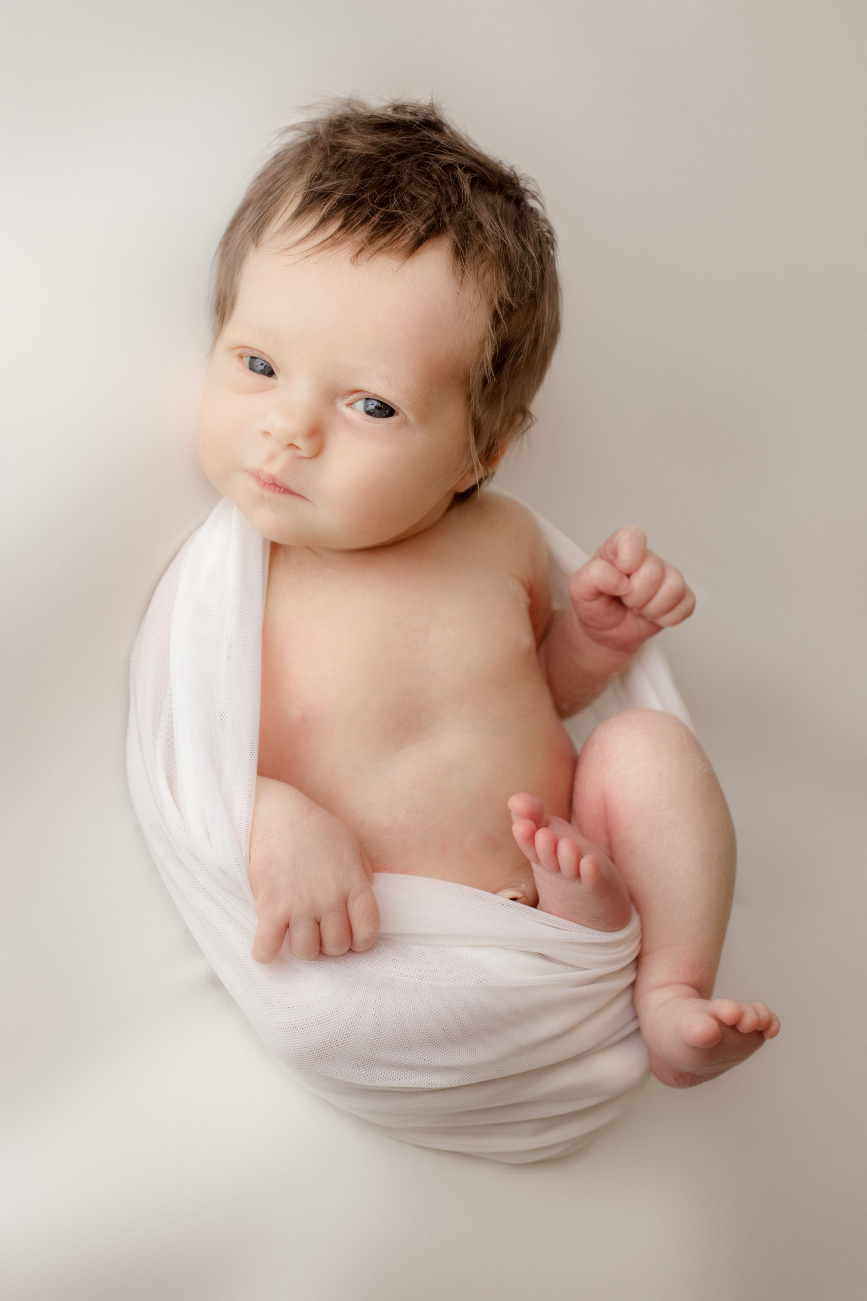 newborn baby girl wrapped in a white wrap during her photos at a Milwaukee photography studio