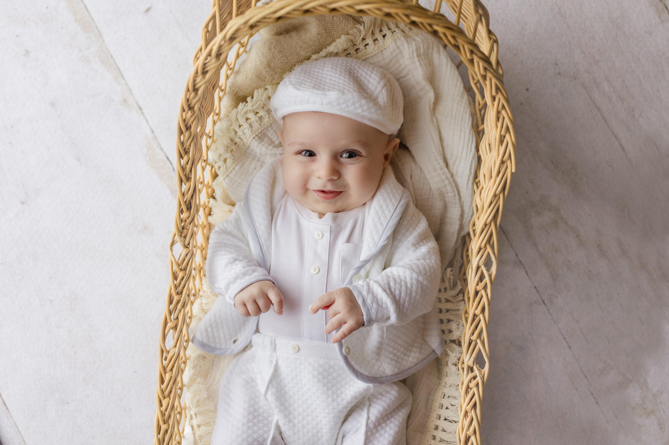 three month old boy in his baptism outfit for pictures in a vintage bassinet taken by Milwaukee family photographer