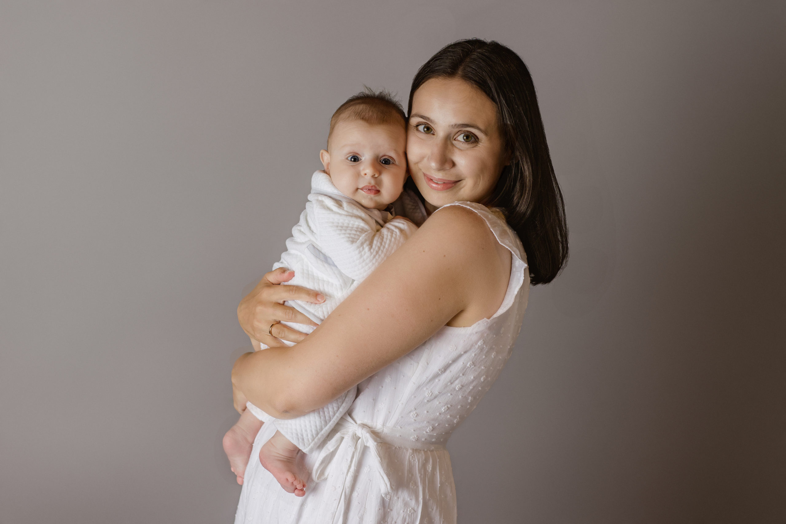 three month old baby boy with his mom in a photo where they are both wearing white in Milwaukee photographer studio