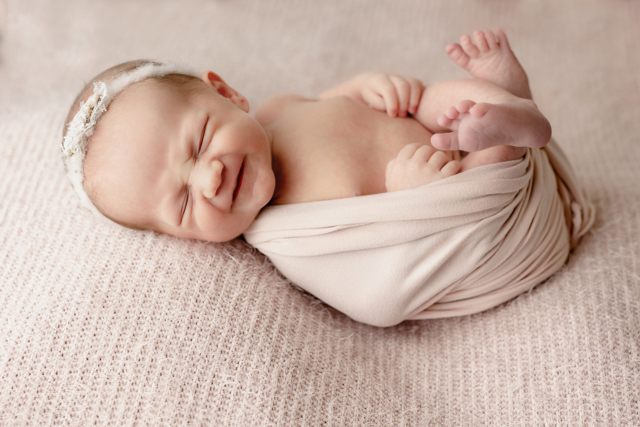 newborn baby girl on a soft pink blanket during newborn photos in Milwaukee