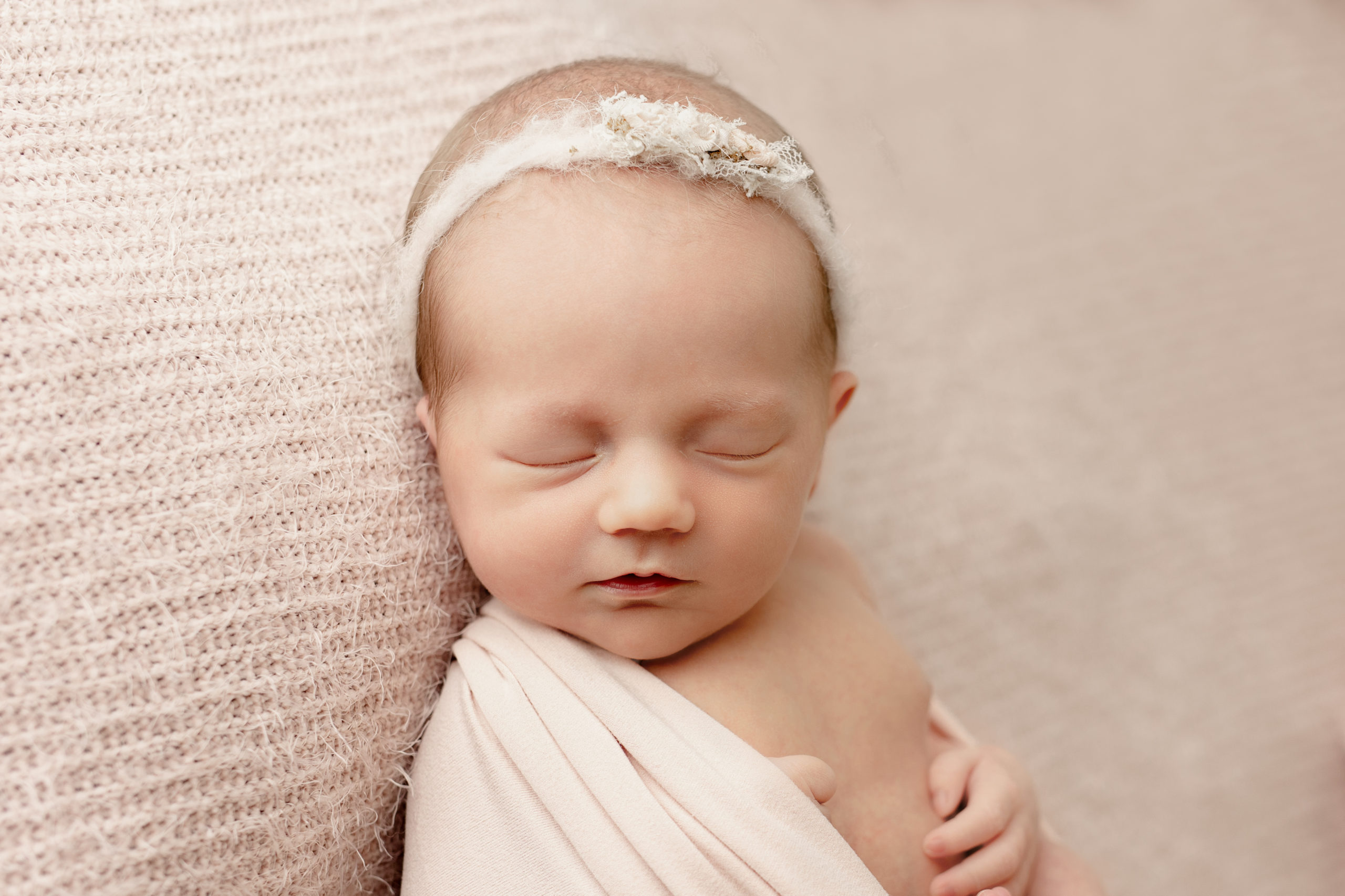 close up image of newborn girl with a light pink headband on in a photo taken by brookfield newborn photographer