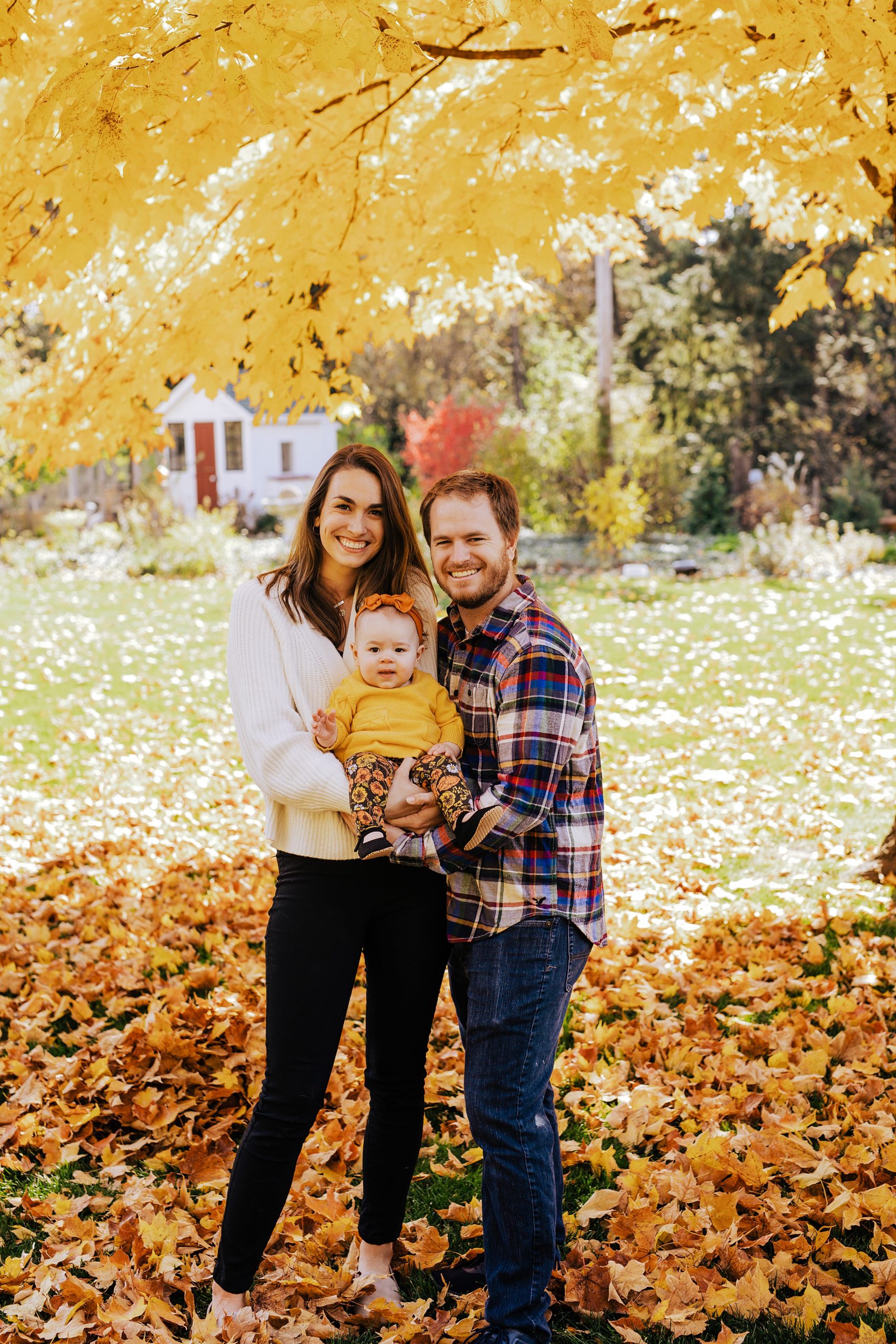 mom and dad holding their little girl outside in the fall weather Shorewood Family Chiropractic