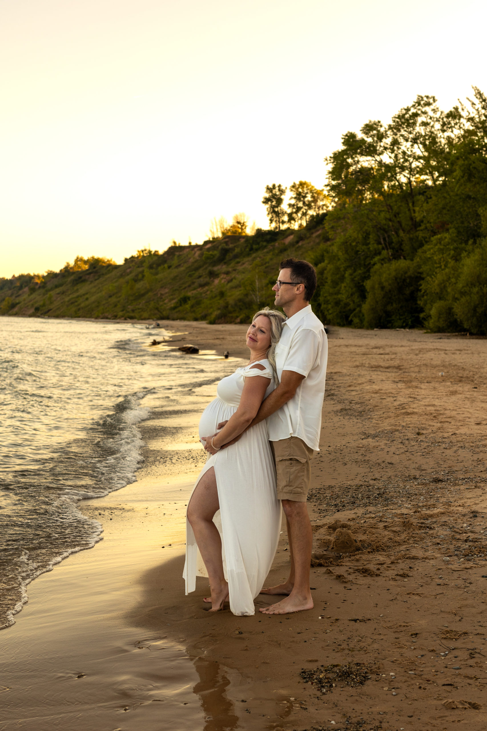 mom and dad to be holding each other near the water Vios Fertility Milwaukee