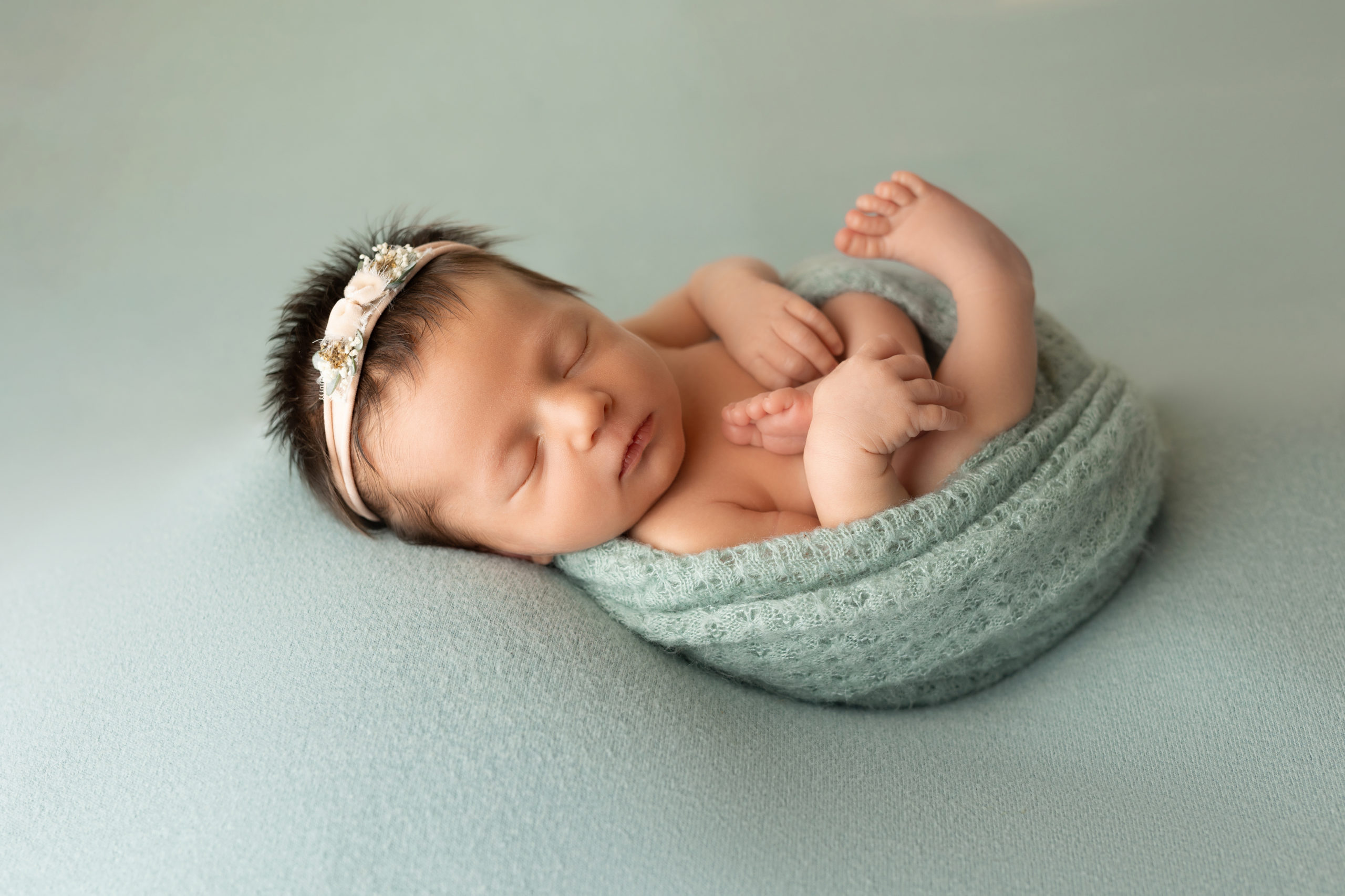 newborn baby wrapped in blue sleeping on her back Infant Swim Lessons Milwaukee