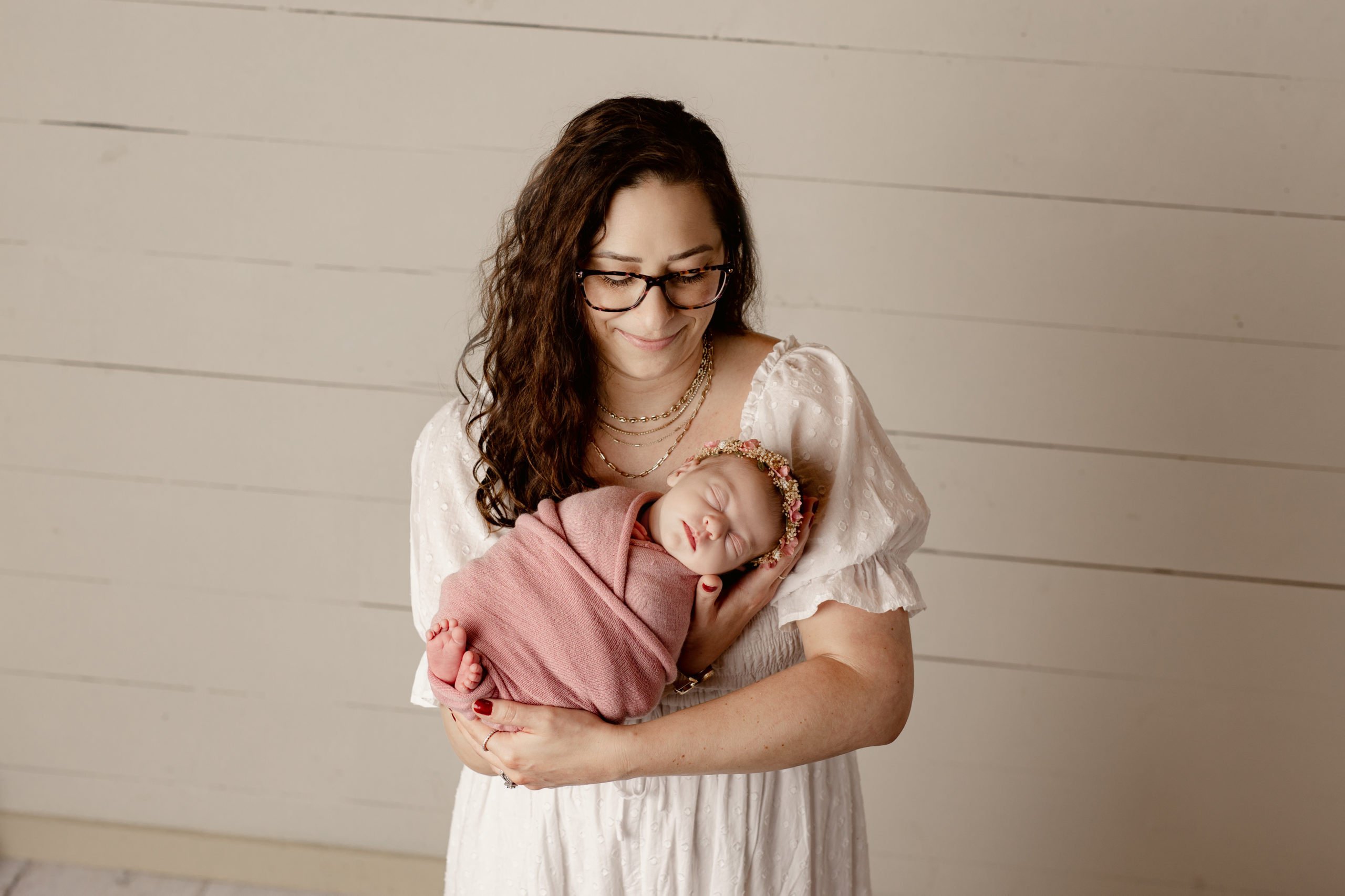 new mom holding her newborn baby girl wrapped in pink Milwaukee Fertility Clinic