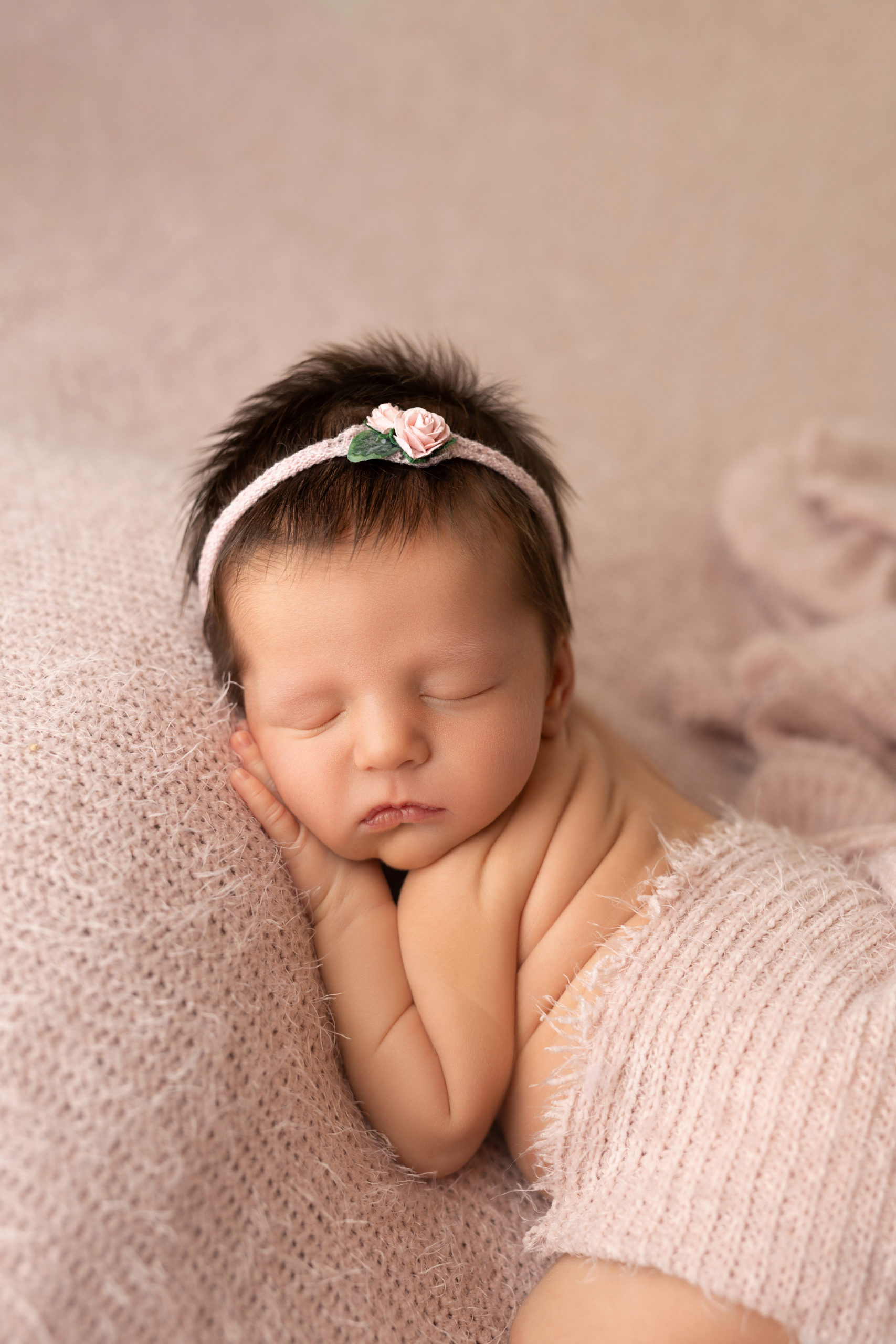 newborn baby in pink with a headband sleeping