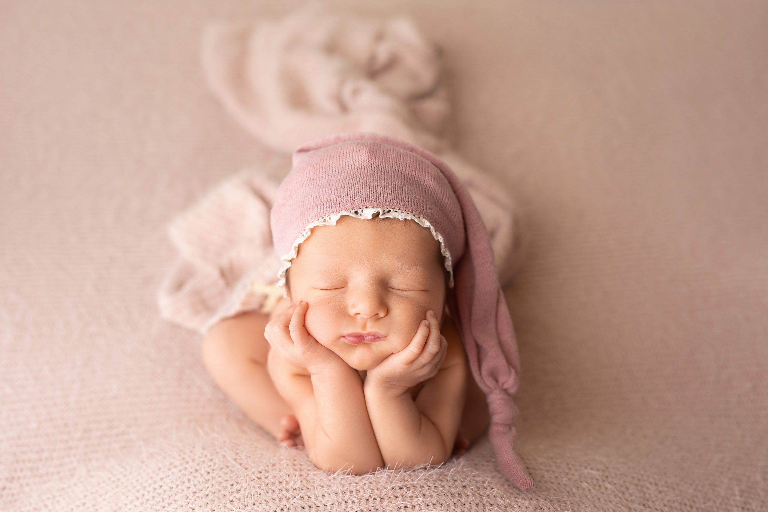 newborn baby girl in pink with her head in her hands diaper service Milwaukee