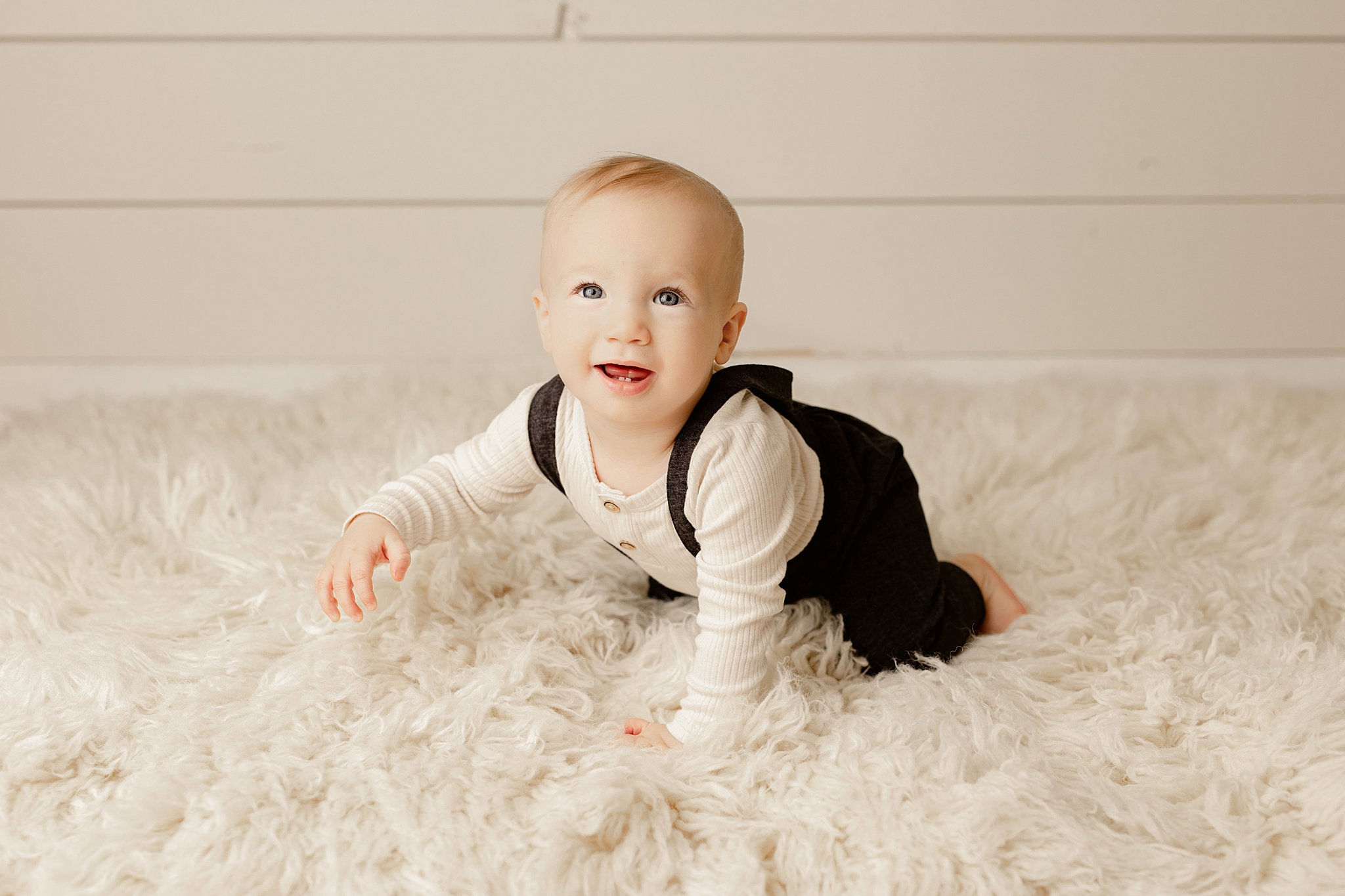 Young baby boy crawls on white shag rug