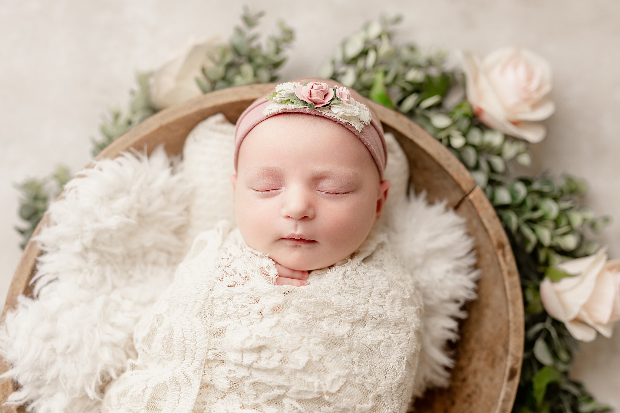 newborn baby girl wrapped in white sleeping in a basket doula waukesha wi