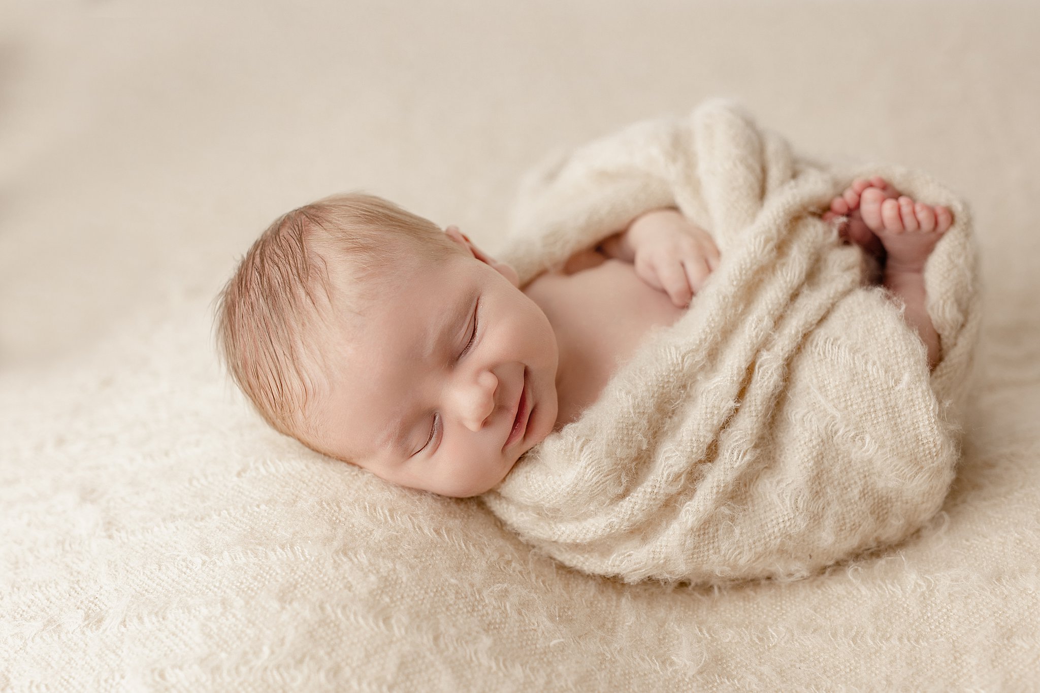 newborn baby wrapped in a warm cream blanket