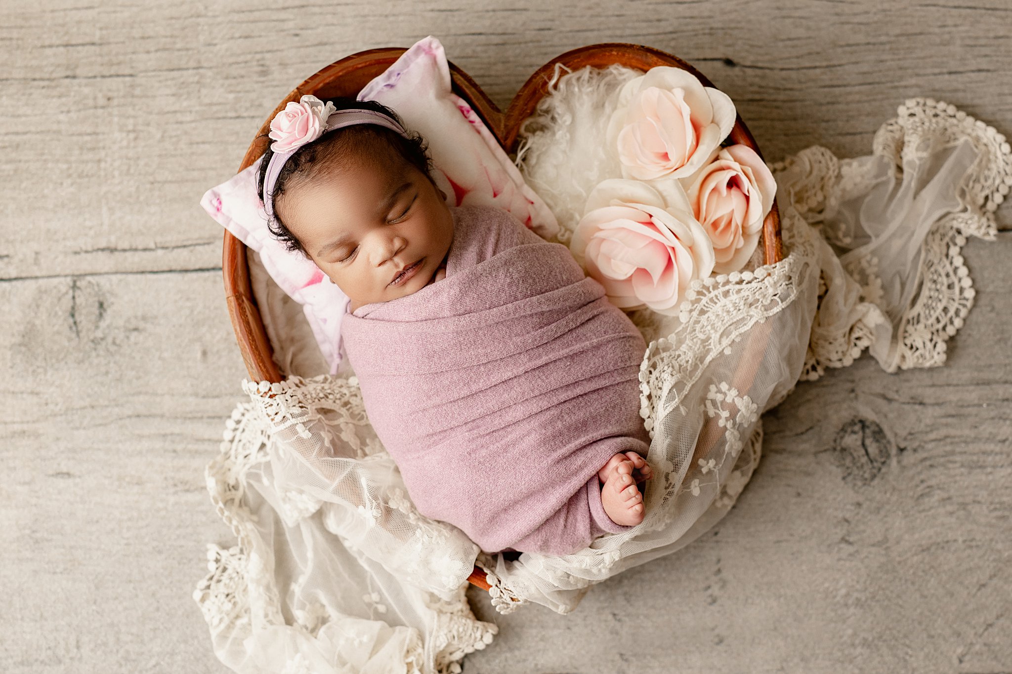 newborn baby girl wrapped in pink laying in a heart bowl waukesha obgyn