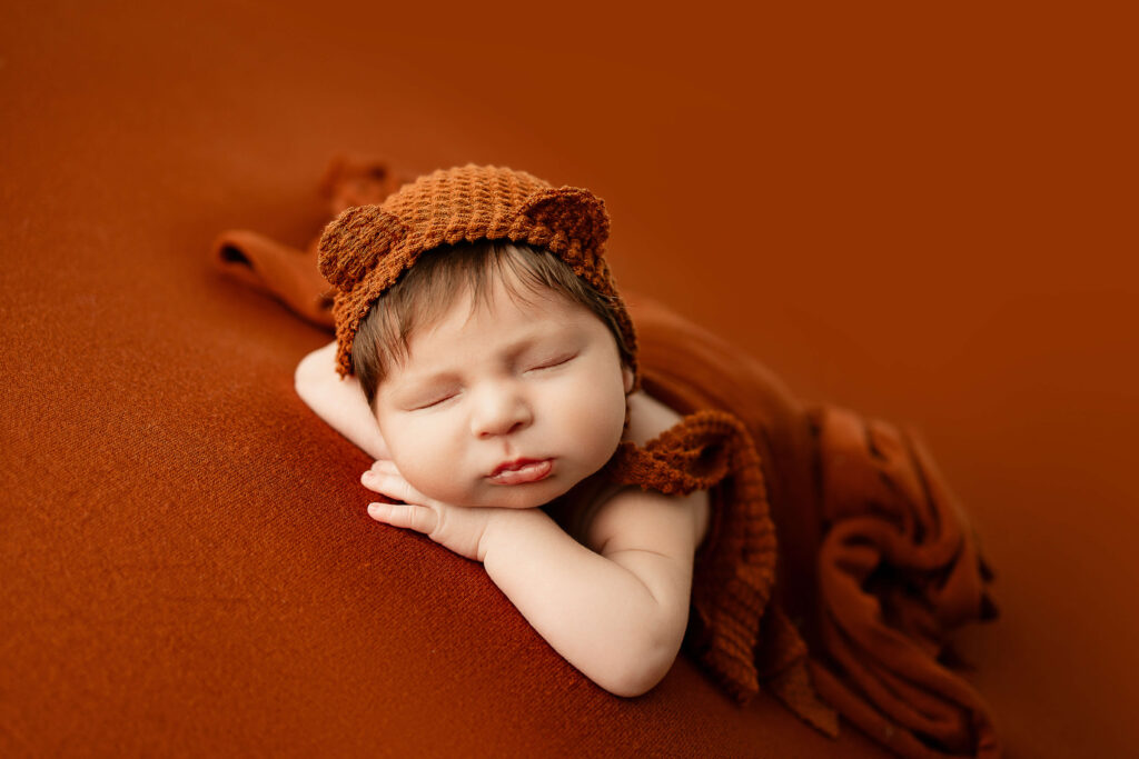 newborn baby boy posed on an jewel tones backdrop at a brookfield newborn photography studio